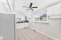 White cabinetry, tile flooring, ceiling fan, and a window with blinds - 