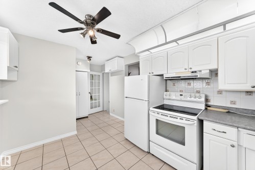 White kitchen cabinetry with complementary white appliances, tile flooring, and a ceiling fan with integrated lighting - 44 Habitat Crescent Nw, Edmonton, AB 