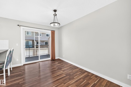 Wood-finish flooring, sliding glass patio door, modern ceiling light fixture, white trim, and light-toned walls - #39 7289 South Terwillegar Nw, Edmonton, AB 