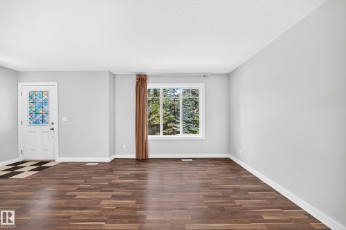 Wood-finish flooring, white trim, light gray walls, large window, and patterned glass front door - #39 7289 South Terwillegar Nw, Edmonton, AB 