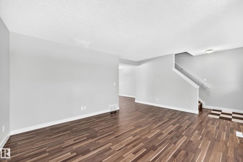 Wood-finish flooring throughout, light gray wall paint, white trim, and a staircase with white railing - #39 7289 South Terwillegar Nw, Edmonton, AB 
