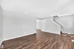 Wood-finish flooring throughout, light gray wall paint, white trim, and a staircase with white railing - 