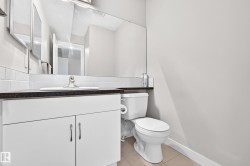 White vanity with dual cabinet doors, integrated sink, dark countertop, and a large wall-mounted mirror - 