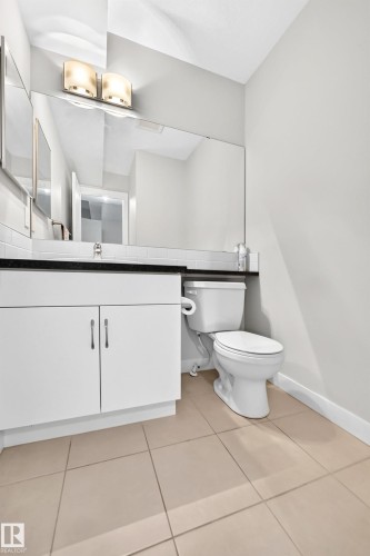 White vanity with dual-door cabinetry, black countertop, and a full-width mirror - #39 7289 South Terwillegar Nw, Edmonton, AB 