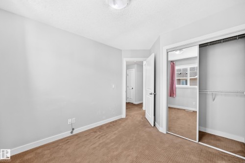 Mirrored closet doors, built-in closet shelving, neutral wall paint, and brown carpeting - #39 7289 South Terwillegar Nw, Edmonton, AB 