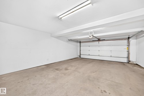 Attached garage featuring a concrete floor, white walls, and a fluorescent ceiling light fixture - #39 7289 South Terwillegar Nw, Edmonton, AB 