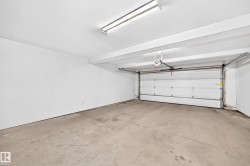 Attached garage featuring a concrete floor, white walls, and a fluorescent ceiling light fixture - 