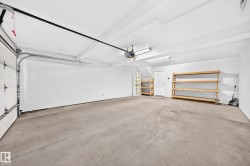 Spacious garage featuring a concrete floor, built-in shelving, and white overhead door - 