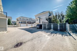 Paved common area with chain-link fencing and mature trees - 
