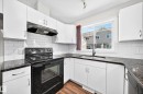 Kitchen featuring white cabinetry, dark countertops, white subway tile backsplash, and wood-finish flooring - #39 7289 South Terwillegar Nw, Edmonton, AB 