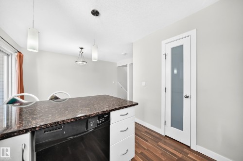 Kitchen island with dark countertop, integrated dishwasher, and white cabinetry - #39 7289 South Terwillegar Nw, Edmonton, AB 