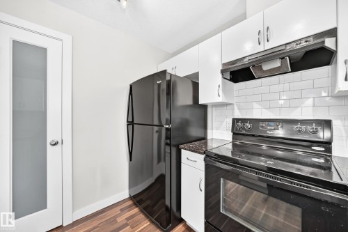 Dark wood-finish flooring complements the white cabinetry and white subway tile backsplash - #39 7289 South Terwillegar Nw, Edmonton, AB 
