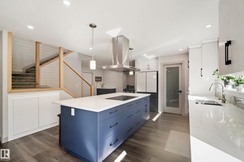 Kitchen featuring a blue island with a built-in cooktop, stainless steel range hood, white countertops, and wood-finish flooring - 49279 Rge Rd 240, Rural Leduc County, AB 