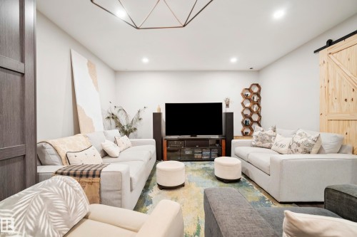 Recessed lighting, wood-finish barn door, geometric ceiling light fixture, television media console, and built-in honeycomb shelving - 49279 Rge Rd 240, Rural Leduc County, AB 