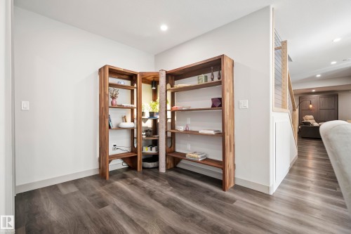 Integrated wood-finish shelving with multiple display levels, recessed ceiling lighting, wood-finish flooring, and a stairway with horizontal slat railing - 49279 Rge Rd 240, Rural Leduc County, AB 
