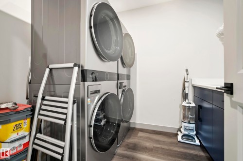 Laundry area featuring wood-finish flooring, white walls, and dark cabinetry with a light-colored countertop - 49279 Rge Rd 240, Rural Leduc County, AB 