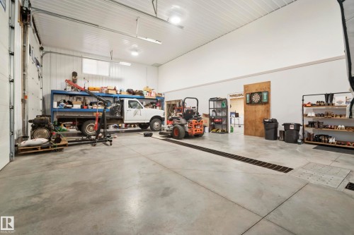 Spacious concrete floor garage with high ceilings, fluorescent lighting, and large overhead doors - 49279 Rge Rd 240, Rural Leduc County, AB 