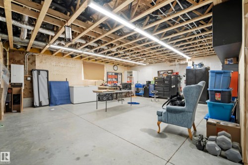 Exposed wood ceiling joists with visible ductwork, concrete flooring, and fluorescent overhead lighting - 49279 Rge Rd 240, Rural Leduc County, AB 