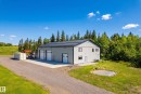 Two-story metal building featuring multiple roll-up doors, a flat roof, and a gravel driveway and home - 49279 Rge Rd 240, Rural Leduc County, AB 