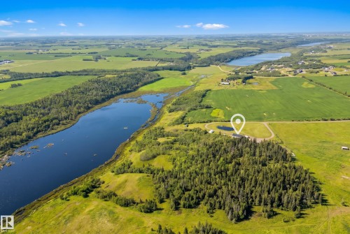 Expansive property featuring a large body of water, surrounding agricultural fields, dense tree coverage, and a distant lake - 49279 Rge Rd 240, Rural Leduc County, AB 