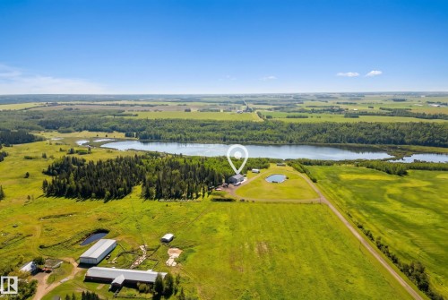 Expansive property featuring a large body of water, dense tree lines, and multiple agricultural structures - 49279 Rge Rd 240, Rural Leduc County, AB 