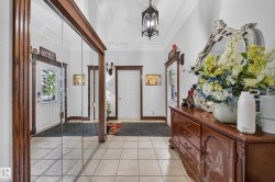 White paneled entry door with sidelight, tile flooring, mirrored closet doors, and crown molding - 