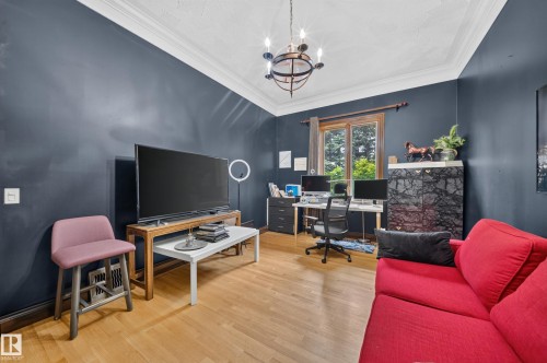 Hardwood flooring complements the dark-toned walls and crisp white crown molding - 719 65 Ave Nw, Edmonton, AB 