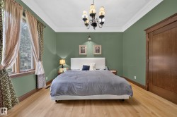 Hardwood flooring with a natural finish, crown molding, wall-mounted sconces, and a window with a wood frame - 