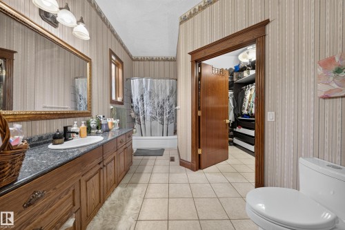 Expansive vanity with a single sink, an ornate framed mirror, and a three-light fixture - 719 65 Ave Nw, Edmonton, AB 