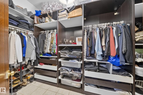 Custom closet system featuring dark wood-finish cabinetry, multiple hanging rods, integrated shelving, and pull-out drawers - 719 65 Ave Nw, Edmonton, AB 
