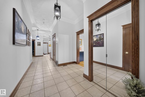 Hallway featuring square tile flooring, decorative ceiling, and dark wood trim - 719 65 Ave Nw, Edmonton, AB 