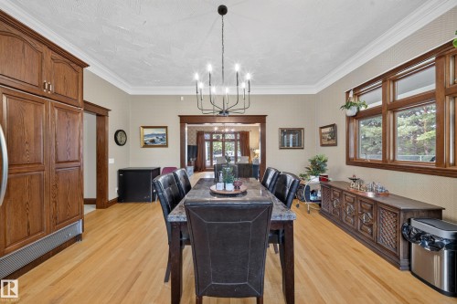 Wood-finish flooring with crown molding, a built-in wood-finish refrigerator, and a multi-light chandelier - 719 65 Ave Nw, Edmonton, AB 