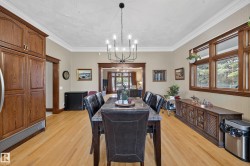 Wood-finish flooring with crown molding, a built-in wood-finish refrigerator, and a multi-light chandelier - 