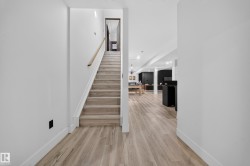 Light wood-finish flooring extending into the lower level, a staircase with wood treads, a wood handrail, and white risers - 