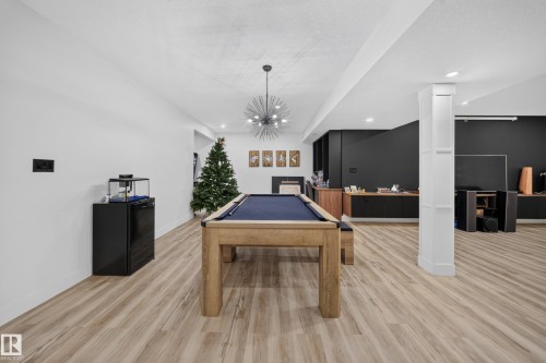 Expansive open-concept room with wood-finish flooring, recessed lighting, and a modern chandelier - 719 65 Ave Nw, Edmonton, AB 