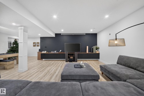 Recessed lighting, wood-finish flooring, built-in media console, accent wall, and wall-mounted light fixture - 719 65 Ave Nw, Edmonton, AB 