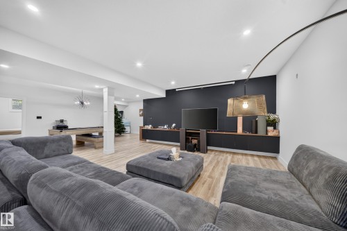 Recessed lighting, wood-finish flooring, built-in media console, black accent wall, and a game area with a pool table - 719 65 Ave Nw, Edmonton, AB 