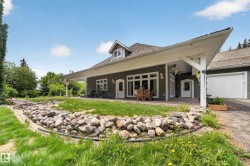 Gray siding exterior with white trim, covered patio, multiple glass panel doors, attached garage, and a gable dormer - 