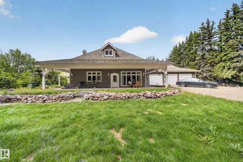 Single-story residence featuring a covered porch, multiple garage bays, and a dormer window - 719 65 Ave Nw, Edmonton, AB 