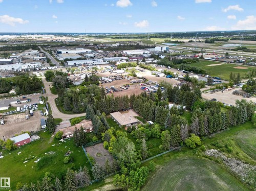 Expansive property featuring a main residence, mature evergreen trees, and a detached outbuilding - 719 65 Ave Nw, Edmonton, AB 