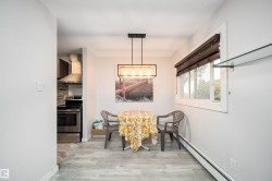 Wood-finish flooring, contemporary chandelier, bright window with blinds, and glass shelving - 