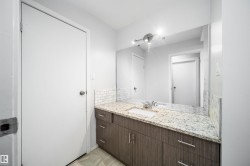 Vanity with wood-finish cabinetry, granite-style countertop, and subway tile backsplash - 