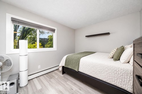 Light gray walls, wood-finish flooring, and a window with blinds - #202 10615 156 St Nw, Edmonton, AB 