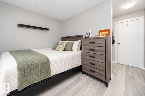 Light-toned wood-finish flooring, a contemporary floating shelf, and a built-in overhead light fixture - #202 10615 156 St Nw, Edmonton, AB 