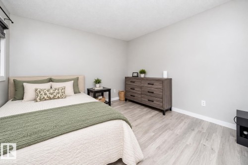 Light-toned wood-finish flooring, neutral wall tones, and a window with roller shades - #202 10615 156 St Nw, Edmonton, AB 
