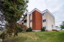 Multi-level building with brick and stucco exterior, white trim, and multiple balconies with white railings - #202 10615 156 St Nw, Edmonton, AB 
