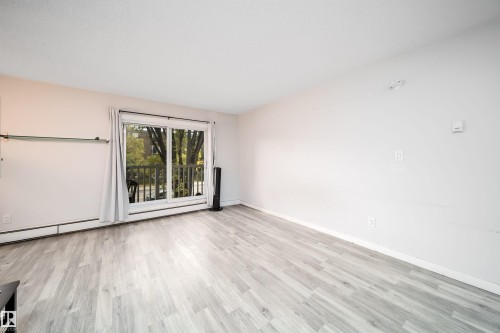Light-toned wood-finish flooring complements the neutral wall color - #202 10615 156 St Nw, Edmonton, AB 