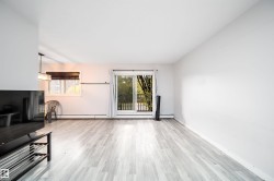 Expansive room featuring light wood-finish flooring, a sliding glass door leading to a balcony, and a prominent window - 