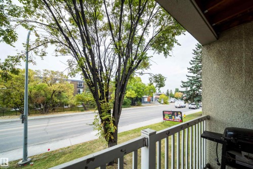 Balcony with textured exterior wall, white railing, and tree-lined streetscape - #202 10615 156 St Nw, Edmonton, AB 