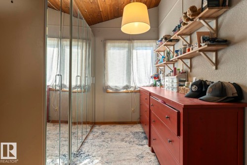 Sloped wood-paneled ceiling, multiple windows, built-in mirrored wardrobe, built-in open shelving, and integrated drawer storage - #421 61209 Rge Rd 465, Rural Bonnyville M.D., AB 